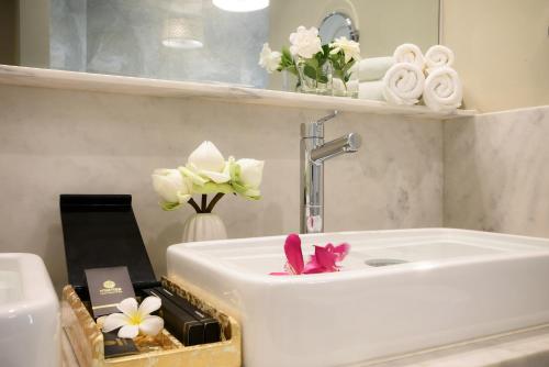 暹粒梅莫瑞度假酒店及Spa的浴室设有白色水槽、鲜花和毛巾