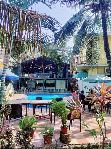 坎多林JV HOLIDAY HOME CANDOLIM的一座拥有游泳池、棕榈树和植物的度假村