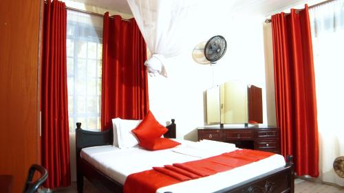 MaragoliKisumu Boutique Hotel的一间卧室配有一张带红色窗帘和镜子的床