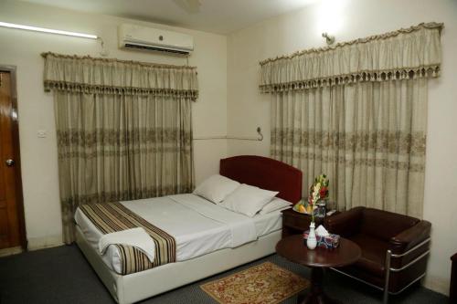 达卡city Homes的一间卧室配有一张床、一张桌子和窗帘