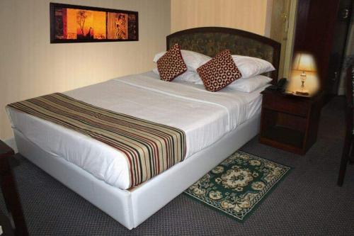 达卡city Homes的卧室配有一张白色床、床头柜和一张四柱床