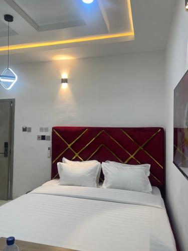 哈科特港HighX Hotels的一间卧室配有一张白色大床和红色床头板