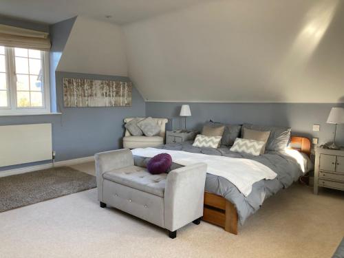 BartleyLangford farmhouse - Luxury 4bd, hot tub, cinema, 10 acres的一间卧室配有一张大床和一把椅子