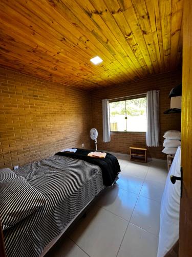 多明戈斯马丁斯Chalé do Lago 1的一间卧室设有一张木天花板床。