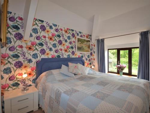 Ugborough2 Bed in Bigbury-on-Sea KEMTH的一间卧室配有蓝色的床和花卉壁纸