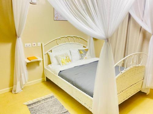 内罗毕Pristine Luxury 2 bedroom Apartment-South C的卧室配有带窗帘的白色天蓬床