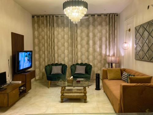拉合尔Homey Stays - 3 Bedroom Holiday Home - DHA的客厅配有沙发、两把椅子和电视