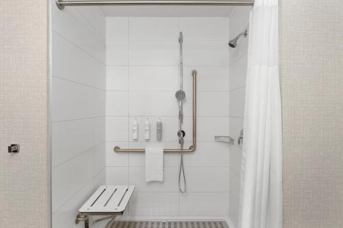 康沃尔Hampton Inn By Hilton Cornwall的浴室设有带长凳和浴帘的淋浴