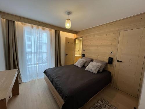 拉普德兹La Terrasse de l Alpe d Huez的一间卧室设有一张黑色的床和一个大窗户