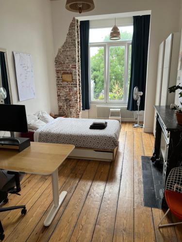 布鲁塞尔Arti Appart Louise/Flagey/Centre的一间卧室配有一张床、一张书桌和一个窗户。