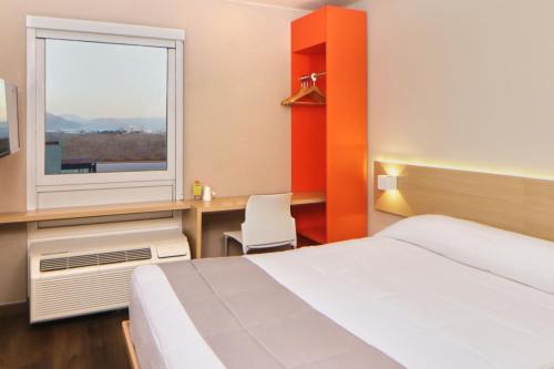提华纳City Express Junior by Marriott Tijuana Otay的酒店客房设有床和窗户。