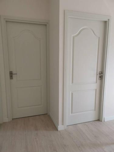 莱卡邦บ้านพักใกล้สุวรรณภูมิ​的空空房间设有两扇白色门,铺有木地板