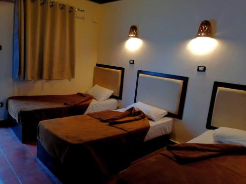达哈布Black Prince camp的一间设有三张床的客房,墙上有灯