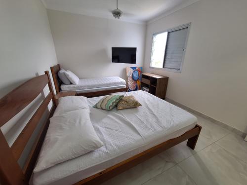 伯迪亚哥Apto em Bertioga , pé na areia的一间卧室配有两张床和电视。
