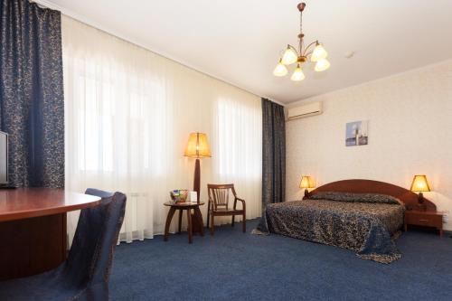 阿克套拉哈特酒店 的酒店客房带一张床、一张桌子和椅子