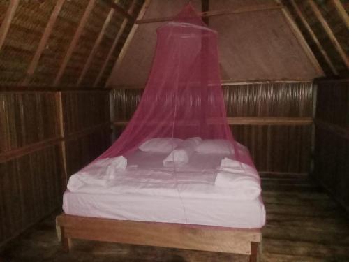 FamOr Mandira Guest House的一张带粉红色天蓬的床