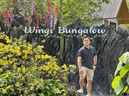 河江Ha Giang Wings Bungalow的站在鲜花标志前的人