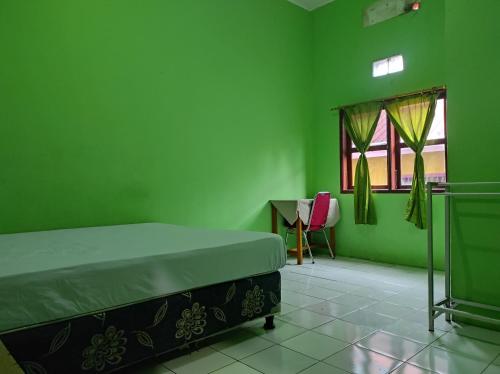 KaremaOYO 93411 Syariah Hotel Tomborang的绿色卧室配有床和书桌