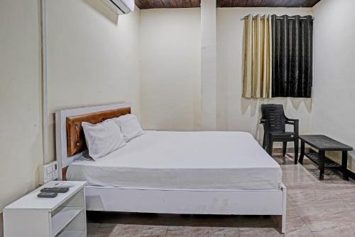 孟买OYO Sai Villa Lodging & Bording的卧室配有1张床、1张桌子和1把椅子