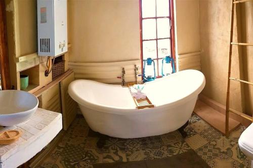 HopefieldFarm Stay: Enjoy Fynbos Views & Wood Fired Hot Tub的带窗户的浴室内的白色浴缸