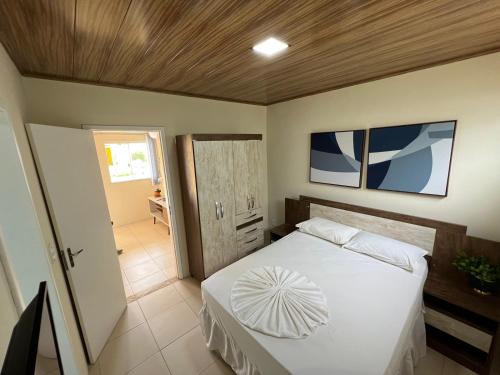 Bôca do RioApartamento em Itaparica的卧室配有白色床和木制天花板