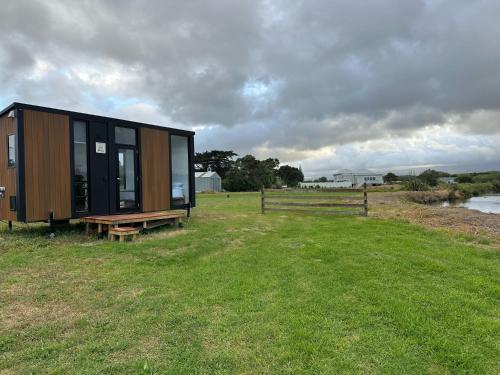 Otaki BeachRangiuru Stream Tiny home的坐在草地顶上的一个小房子