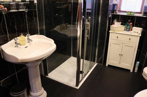 坎贝尔城Gowanlea Heights的一间带水槽和玻璃淋浴的浴室