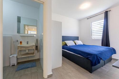 威廉斯塔德Cocobana Resort two-bedroom apartment ground floor的一间卧室配有蓝色的床和水槽