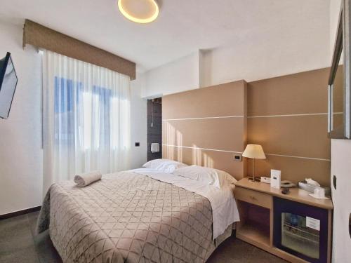 马里纳迪马萨蒂凡尼酒店的一间卧室配有一张床、一张书桌和一个窗户。