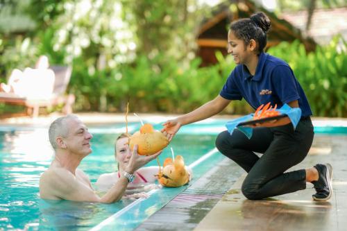 达瓦拉维阿瑟基拉河营地酒店 - 乌达瓦罗的游泳池里的男人,游泳池里的女人,水果