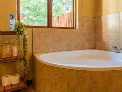 侯斯普瑞特Impala Cottage的带浴缸的浴室和窗户
