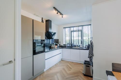 阿姆斯特丹Dutch Design Villa with 6 luxurious bedrooms的一间厨房,配有白色的橱柜和大窗户
