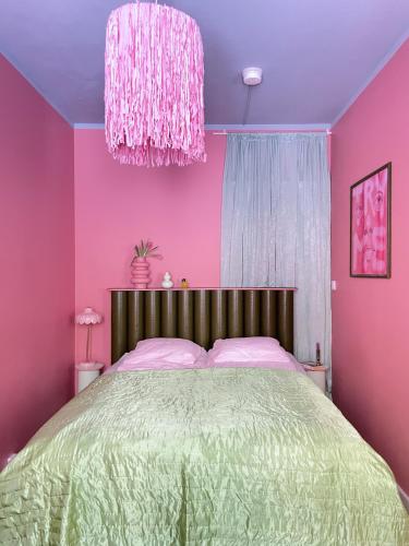 赫尔辛基Värikäs koti lähellä keskustaa的粉红色的卧室配有一张床和吊灯