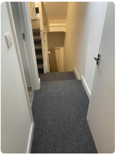 伦敦Lovely room in Tottenham的通往走廊的开放式门,铺有地毯