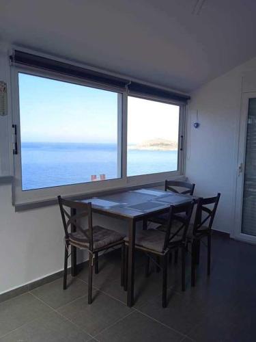 卡利诺岛Kalymnos Platy Gialos Mousellis Makis Apartments的配有大窗户的客房内的桌椅