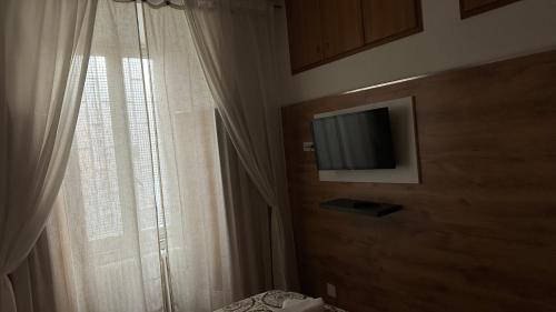 罗马Casa Gemelli的卧室设有窗户,墙上配有电视