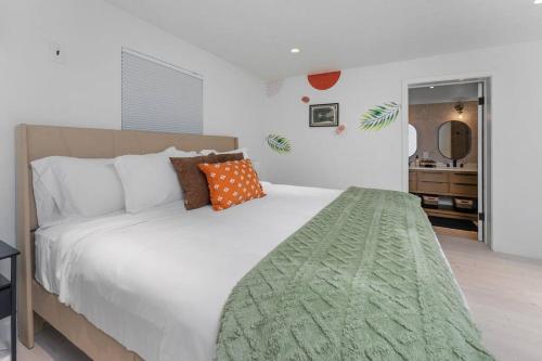 盖恩斯维尔Smart Bungalow: 10-min to UF, Central Location的卧室配有带橙色枕头的大型白色床