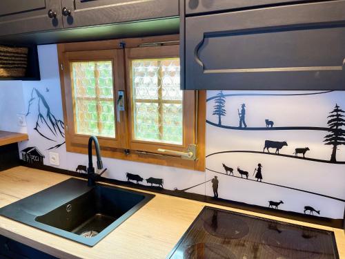 格施塔德Gstaad Chalet的厨房配有水槽,墙上绘有动物