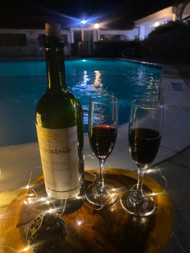 吉拉尔多特里卡德别墅酒店的游泳池畔的一瓶葡萄酒和两杯酒