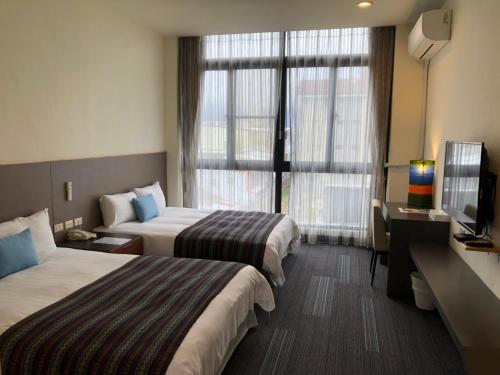 台东Ita taiwan indigenous cultural resort的酒店客房设有两张床和电视。