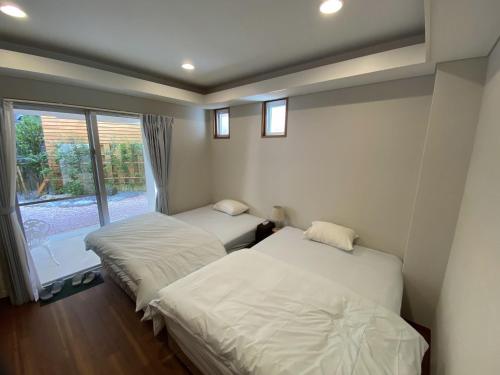 那霸Vacation Rental Kally Naha Okinawa的带窗户的客房内的两张床