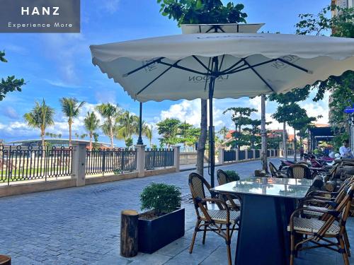 富国HANZ Lagoon Sunset Boutique Hotel的一个带桌椅和遮阳伞的庭院