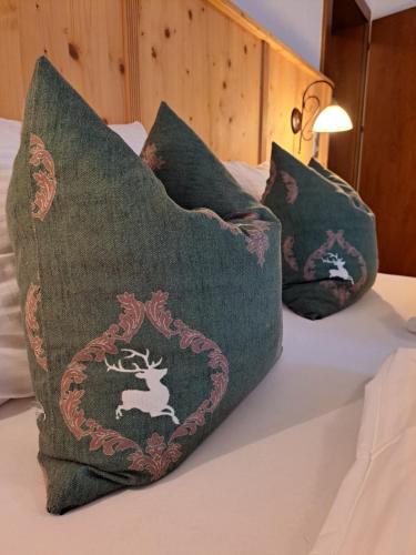 因斯布鲁克Stauders Zimmer und Ferienwohnungen的一张带三个枕头的床,上面有鹿