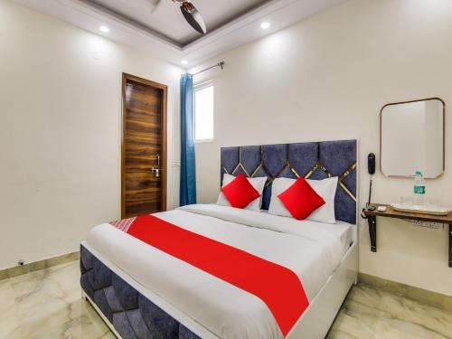 新德里OYO AR Residency的一间卧室配有一张带红色和蓝色枕头的大床