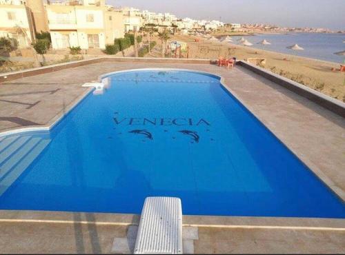 艾因苏赫纳Cozy Villa Venice Ain Sokhna的蓝色游泳池,享有海滩美景