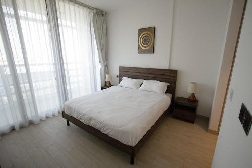 沙迦40 Minutes drive to Burj Khalifa的一间卧室配有一张带白色床单和窗户的床。