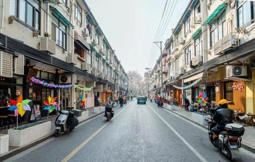 上海上海市中心海派繁花民宿 - 永康路的一条街上,人们骑摩托车,街上有建筑
