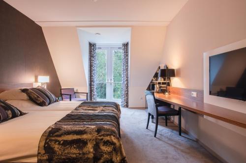 宰斯特Hotel Woudschoten的酒店客房配有一张床、一张书桌和一台电视。
