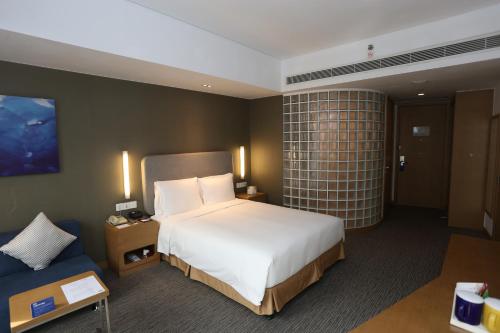 上海上海金沙智选假日酒店的一间卧室配有一张大床和一张蓝色的沙发