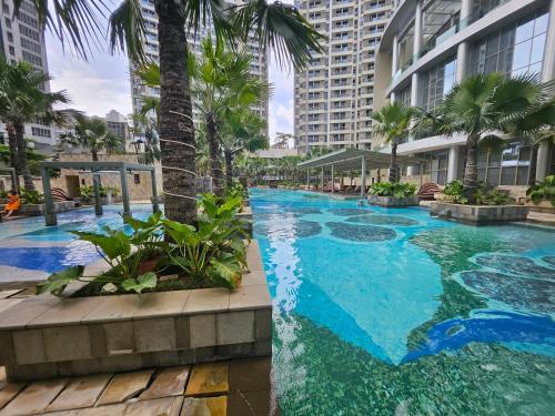 雅加达3BR Flat in Taman Anggrek Residence的一座棕榈树和建筑的大型游泳池